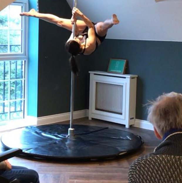 Pole dancer performing acrobatic display at Encore Care Homes for elderly audience 