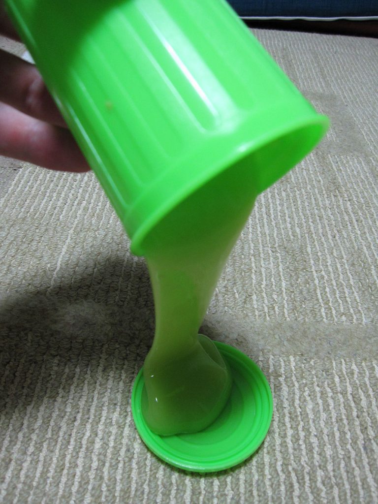 how to make slime: Photo of neon-green slime being poured from a small plastic trash can.
